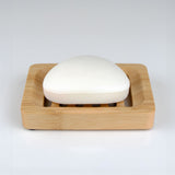 Bar of soap in a wooden soap dish on a white background
