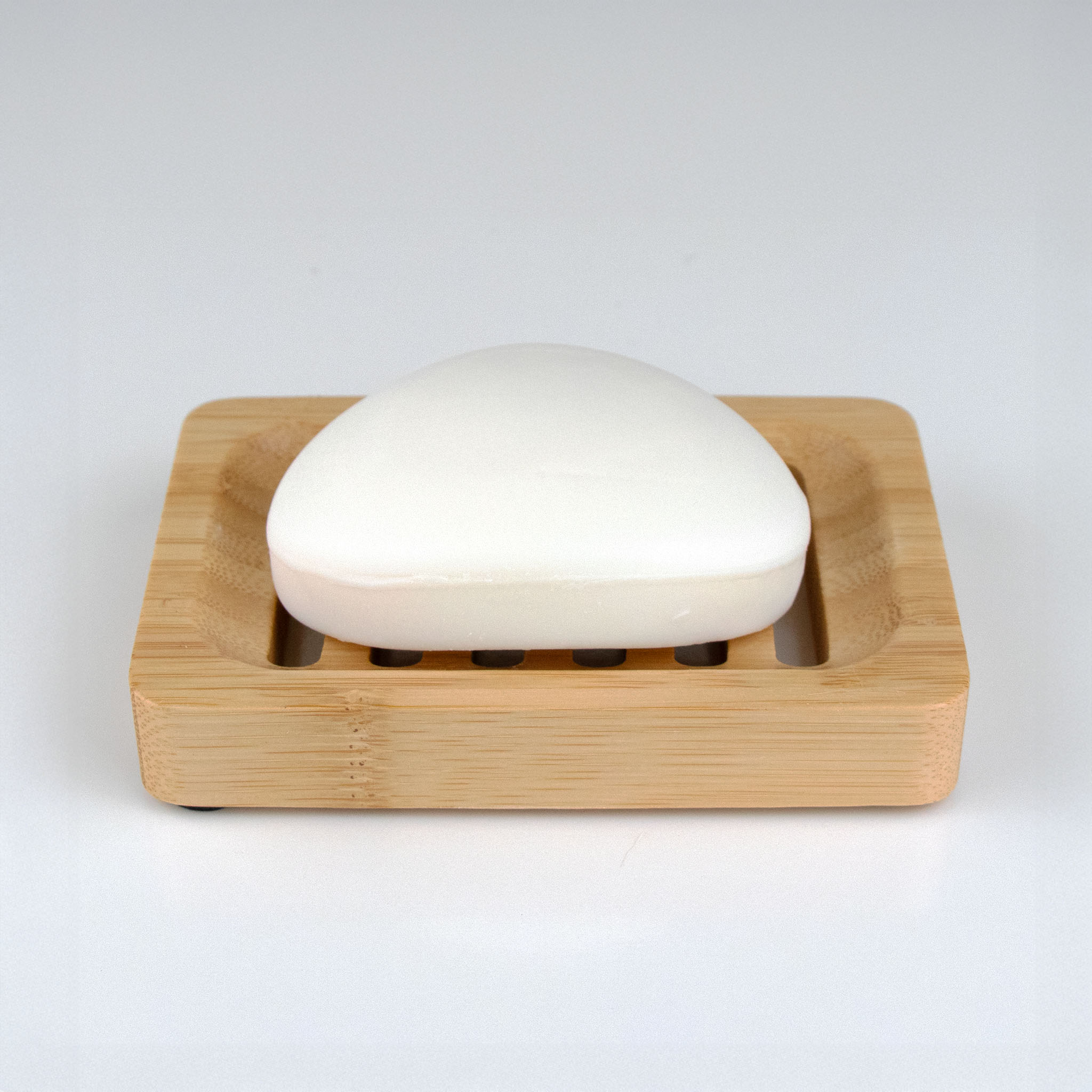 Bar of soap in a wooden soap dish on a white background