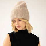 Model wearing an iced taupe knit beanie and black sleeveless top on a white background