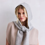 Woman wearing a gray hooded scarf against a plain background