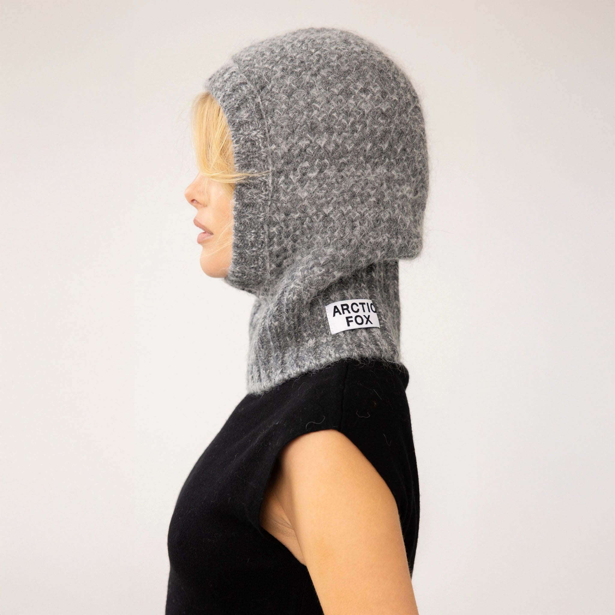 Person wearing a gray knitted balaclava with 'Arctic Fox' label on a white background