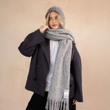 Person wearing a gray scarf and a grey balaclava with a beige background