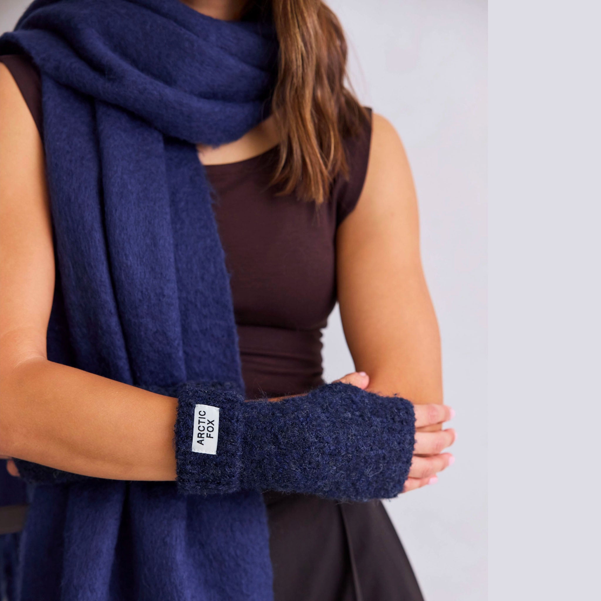 Person wearing a navy blue scarf and matching handwarmers with 'Arctic Fox' label.