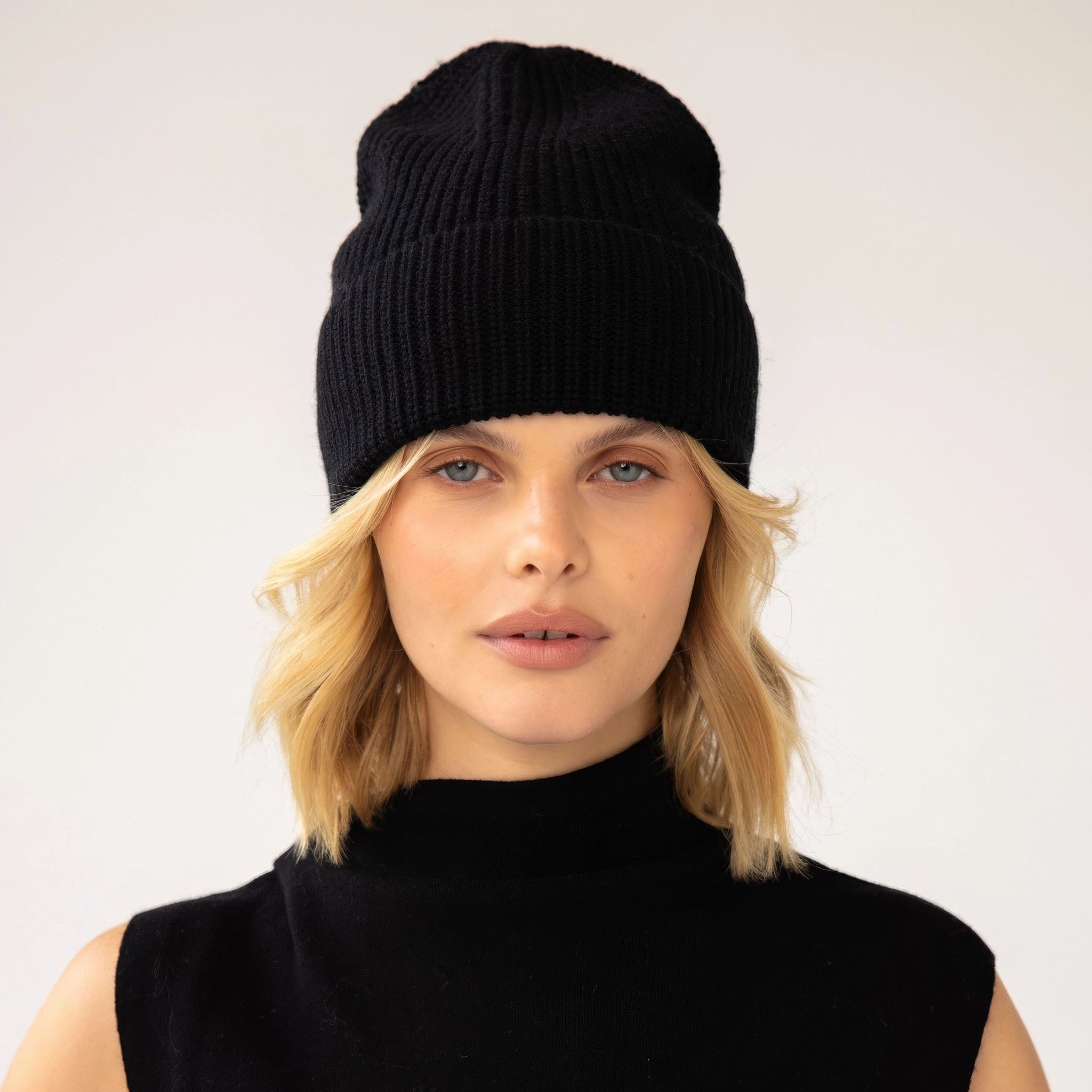 Model wearing a black knit beanie against a plain background