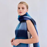 Woman wearing a blue plaid scarf on a plain background