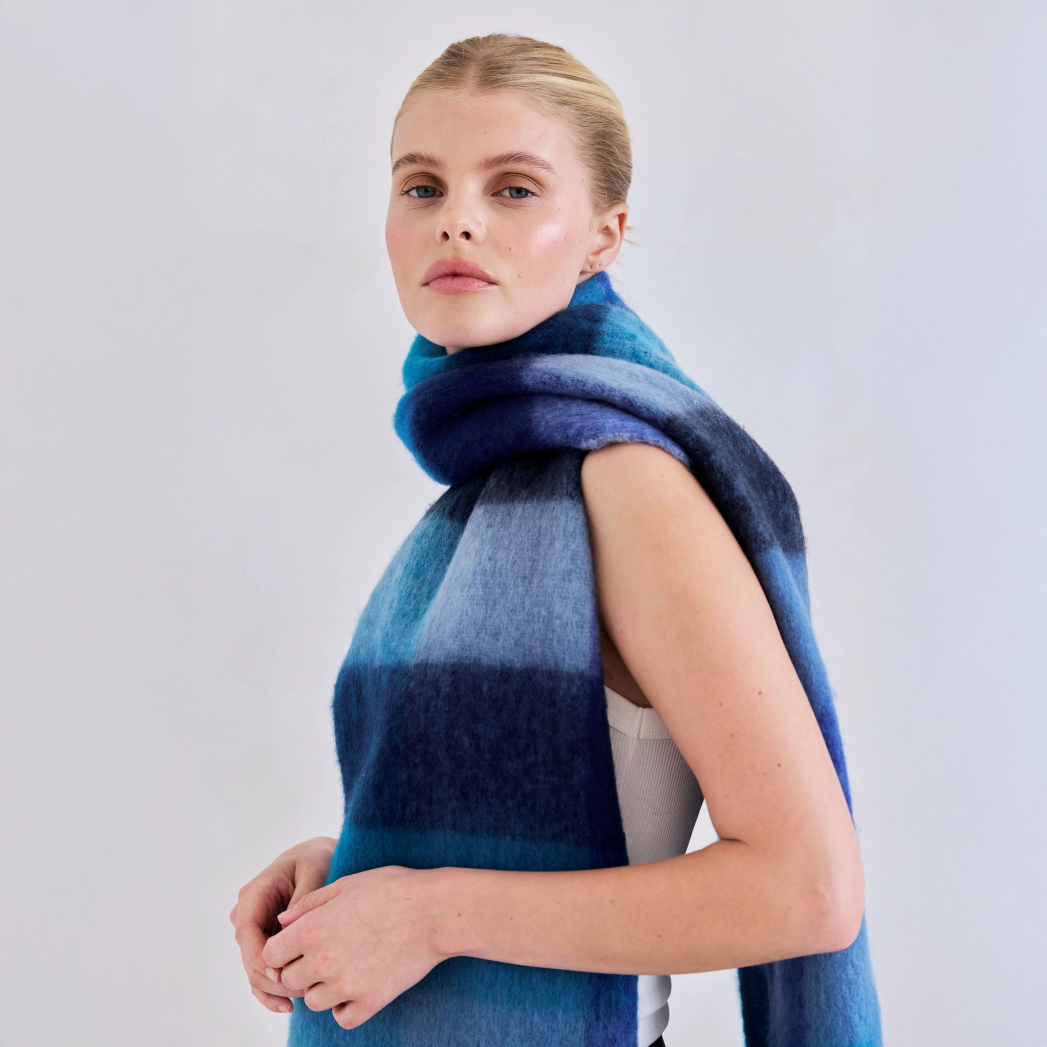 Woman wearing a blue plaid scarf on a plain background