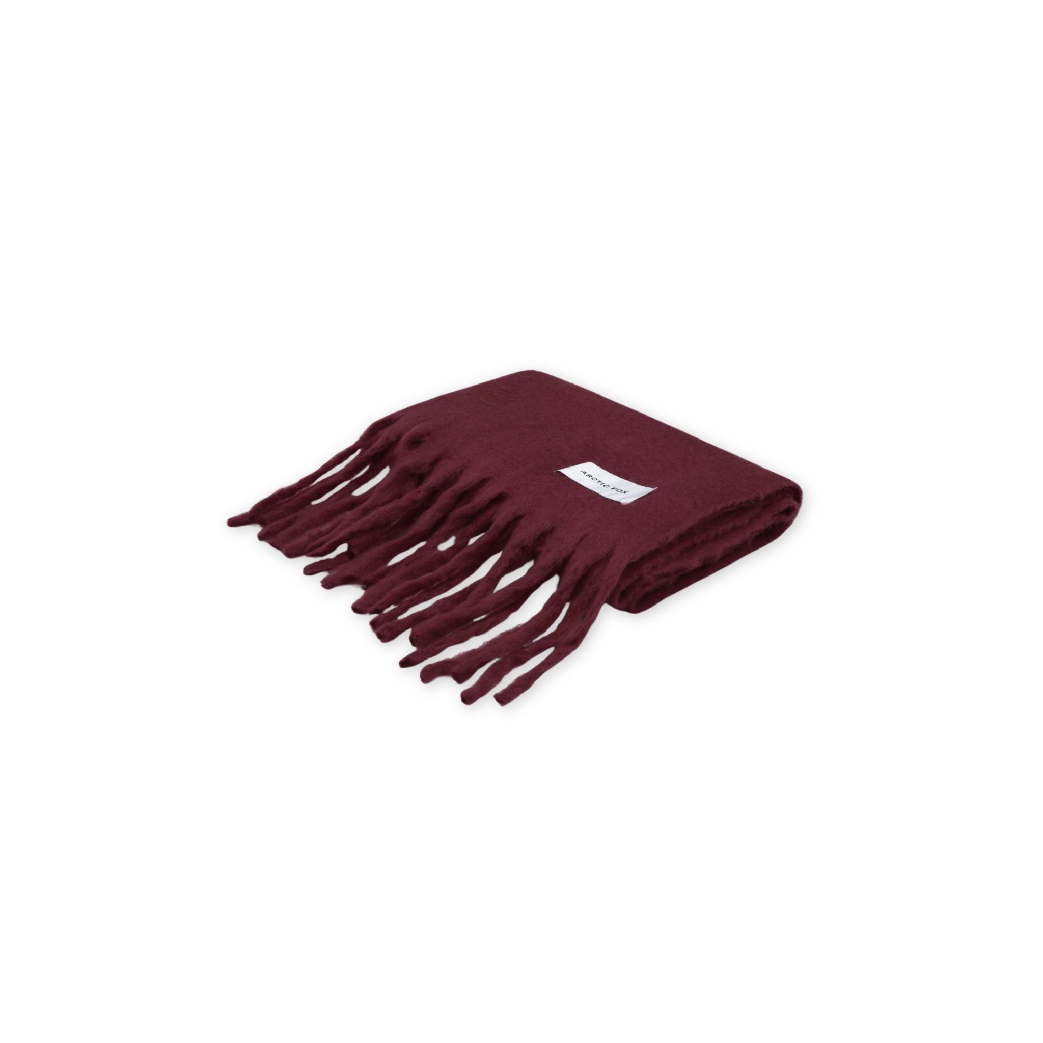 A folded burgundy scarf with fringes on a white background