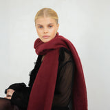 Woman wearing a burgundy scarf against a plain background