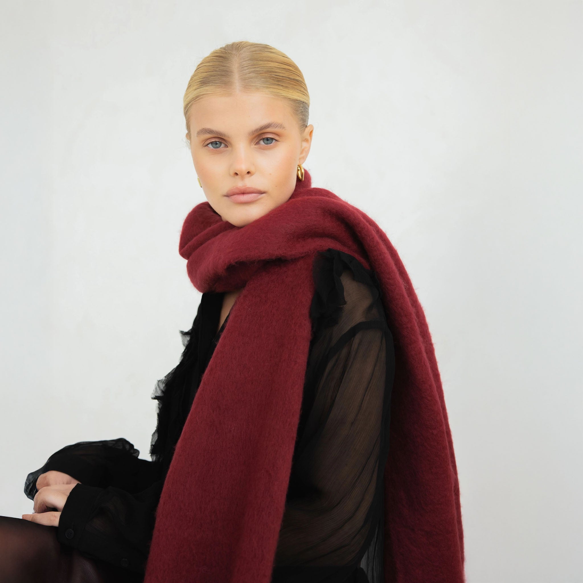 Woman wearing a burgundy scarf against a plain background