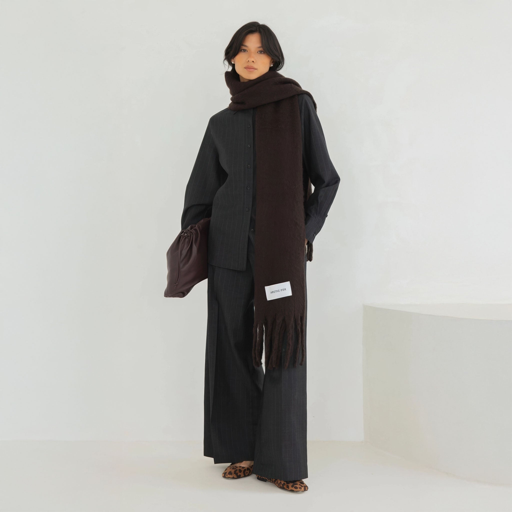 Model wearing a long dark brown scarf with a plain background