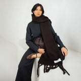 Model wearing a dark brown scarf with a brand label Arctic Fox, sitting on a white surface.