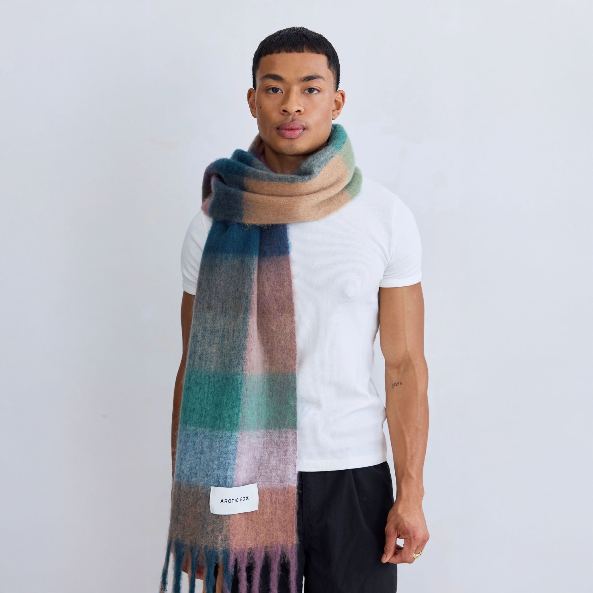 Man wearing a lily plaid scarf with a plain background