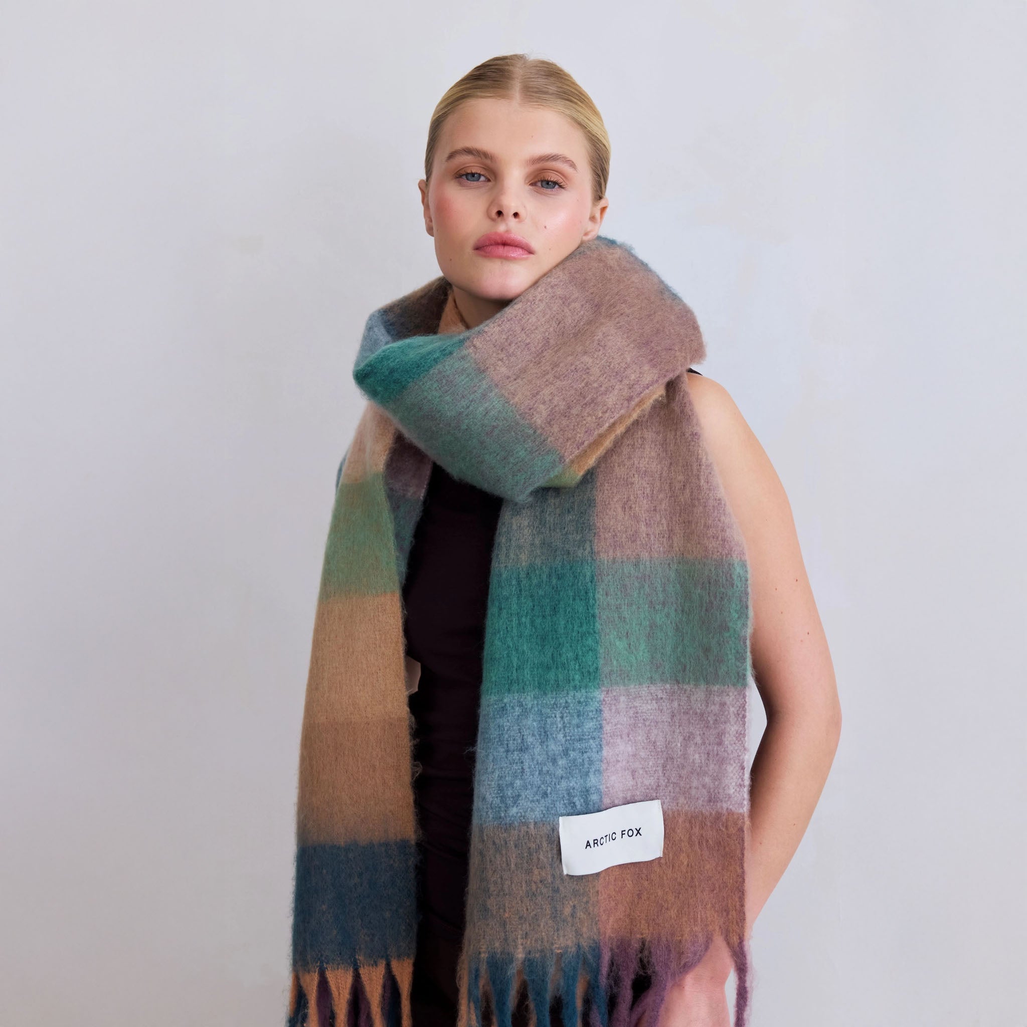 Woman wearing a lily plaid scarf with a visible brand label on a plain background