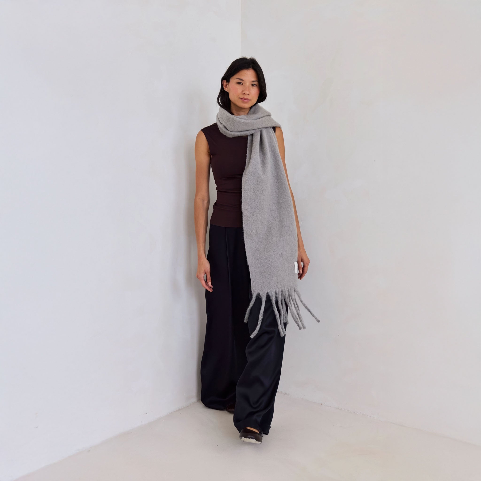 Model wearing a gray scarf against a white background