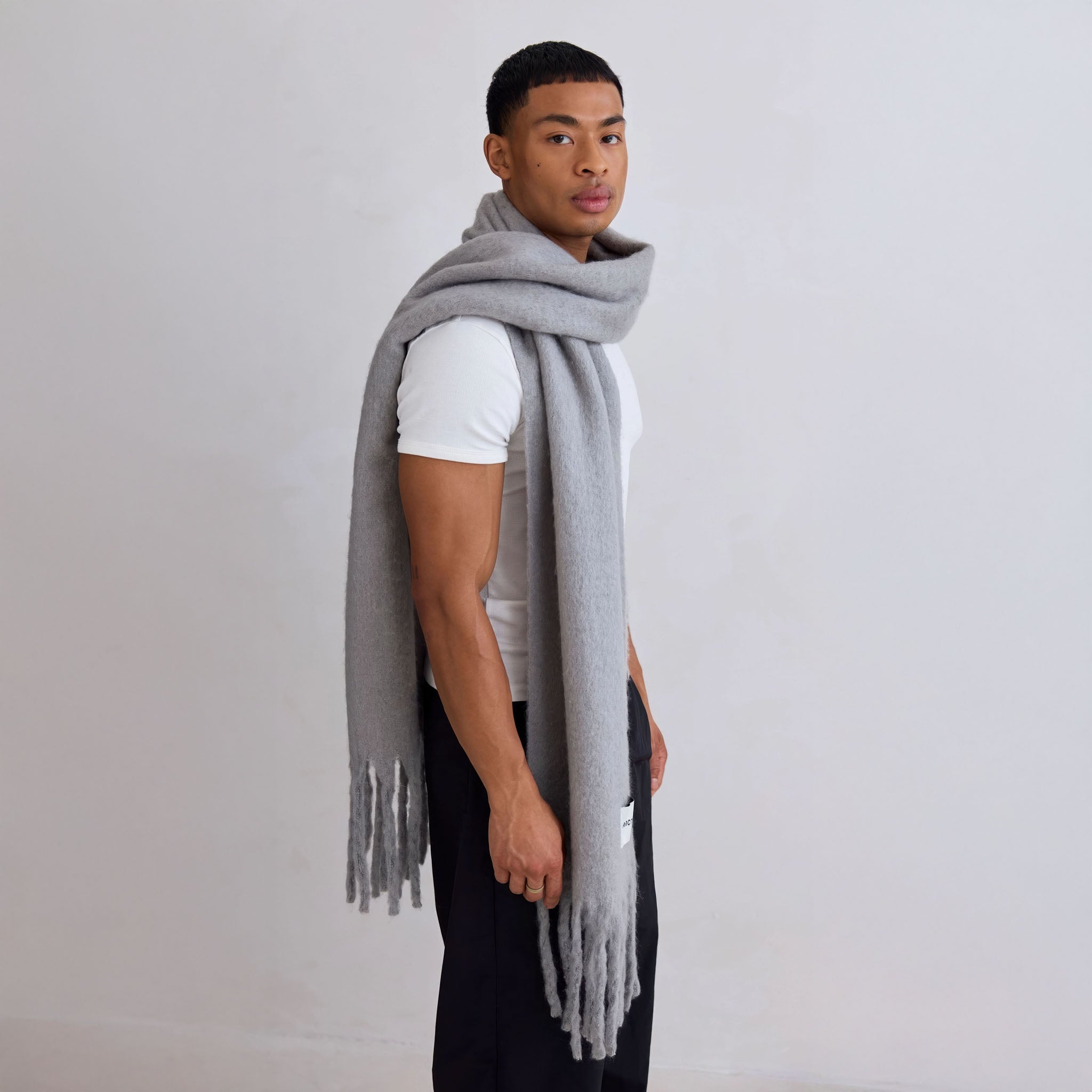 Model wearing a gray scarf against a plain background