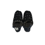 Pair of black slippers with white polka dots on a white background