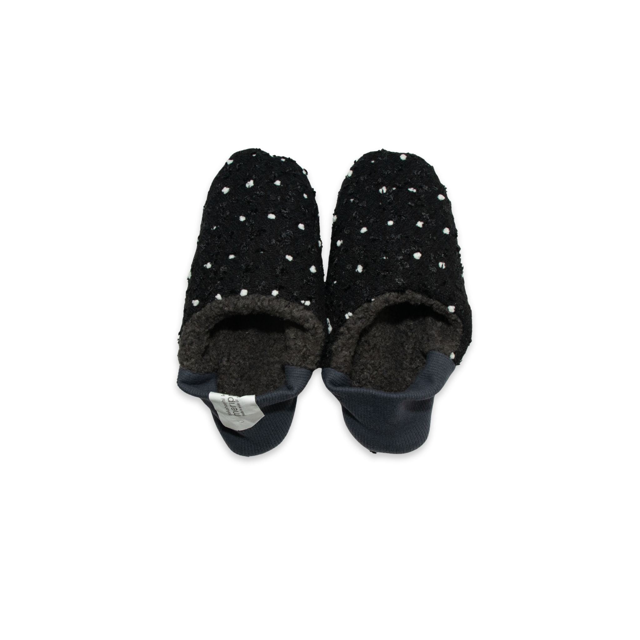 Pair of black slippers with white polka dots on a white background