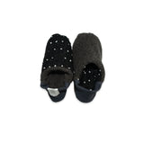 Pair of black slippers with white polka dots on a white background