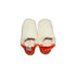 A pair of creme colored  slippers with orange trim on a white background