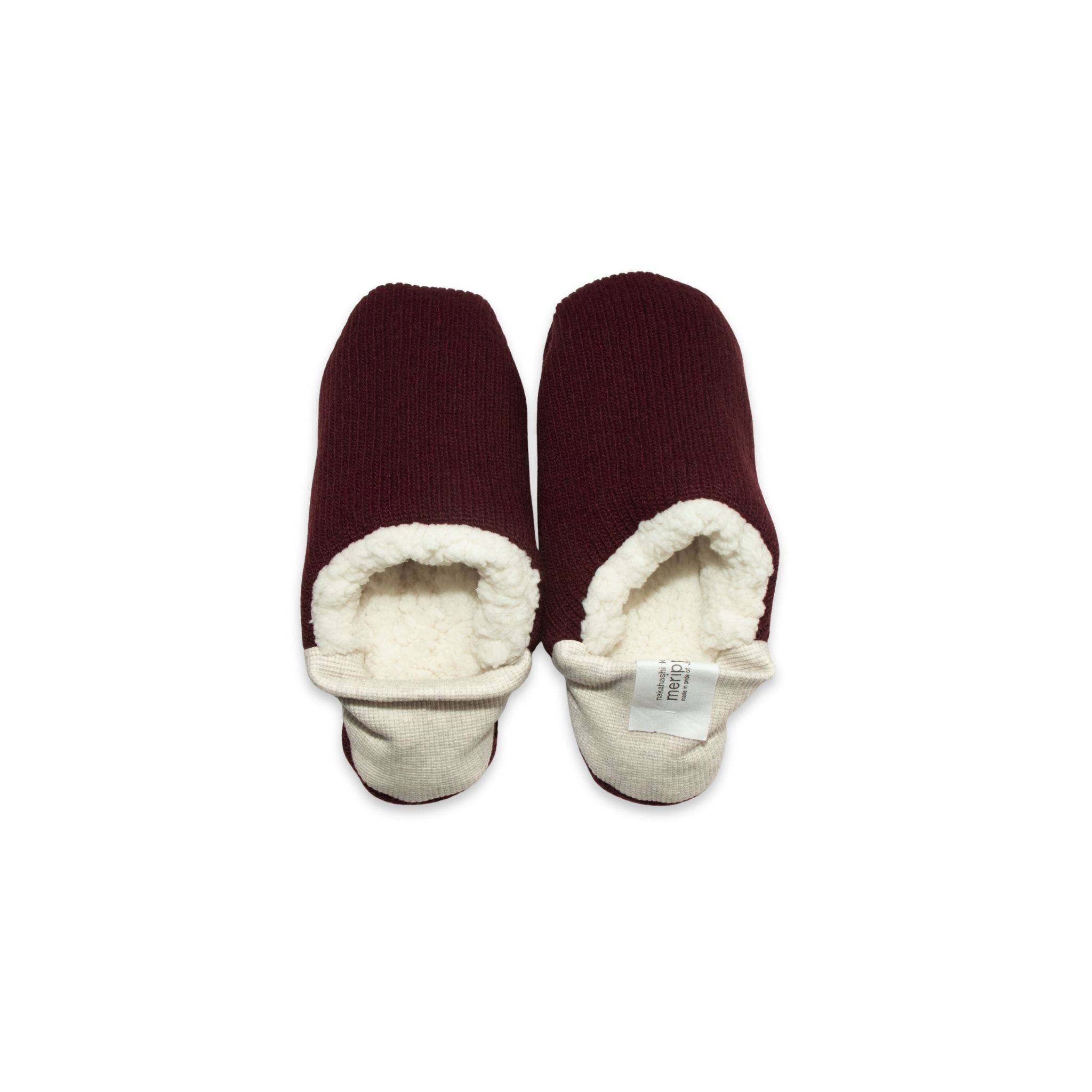 A pair of burgundy colored  slippers with white trim on a white background