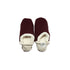 A pair of burgundy colored  slippers with white trim on a white background