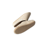 Pair of beige slippers on a white background showing the soles