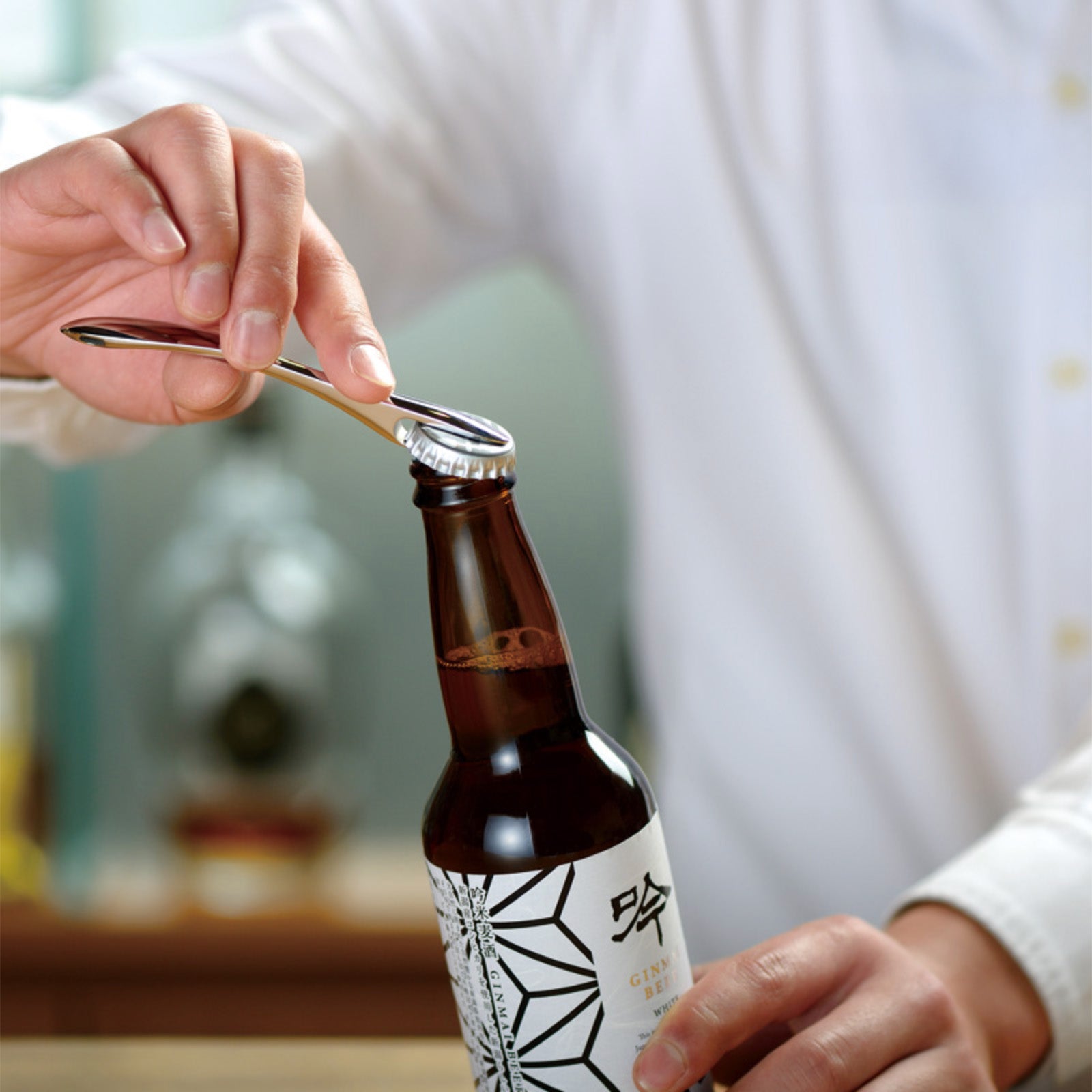 Person opening a beer bottle with the Suwada bottle opener