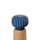 Closeup of a wooden pepper grinder with blue striped top on a white background