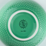 Close-up of a green textured bowl with a brand logo on a white background
