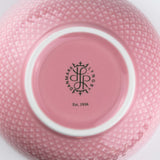 Rose pink ceramic bowl with a visible brand logo and text on a white background