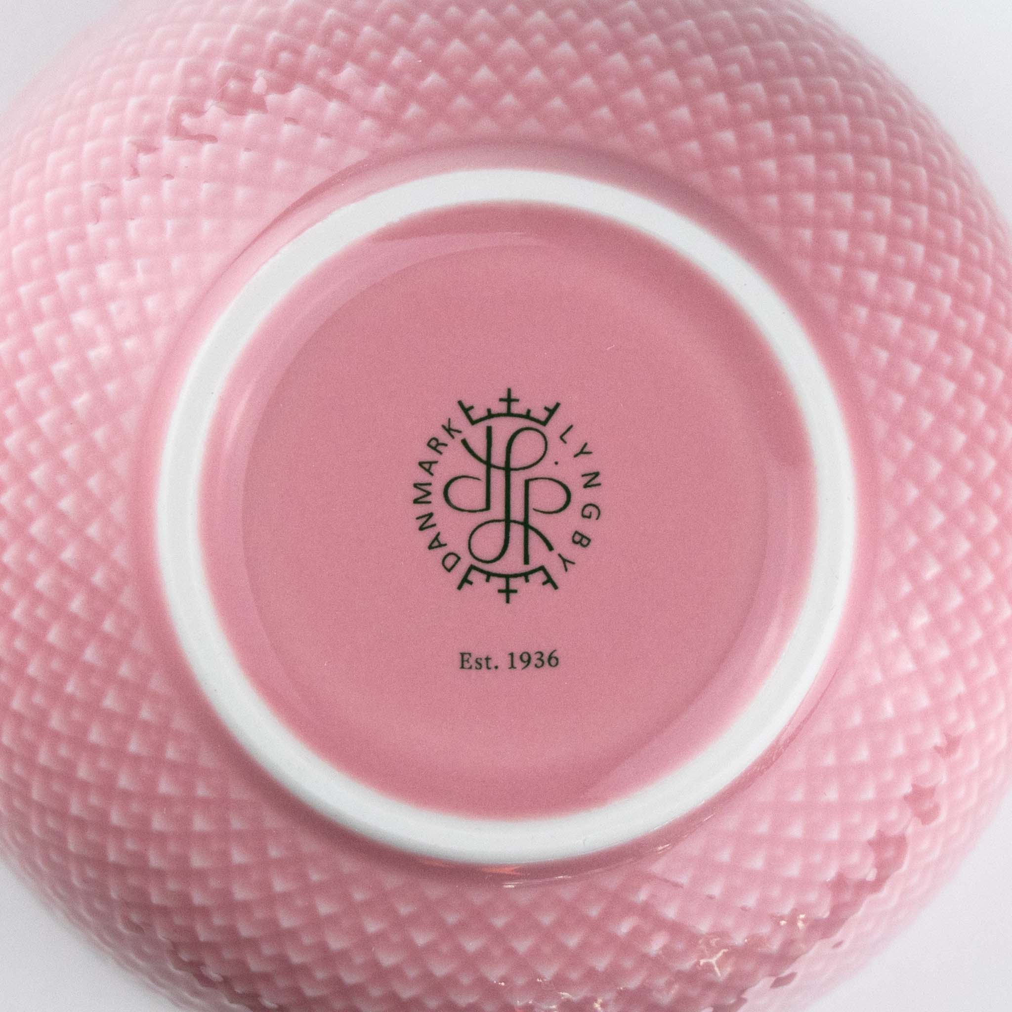 Rose pink ceramic bowl with a visible brand logo and text on a white background