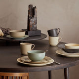 Dining table set with ceramic porcelain bowls, cups, and plates on a wooden table.