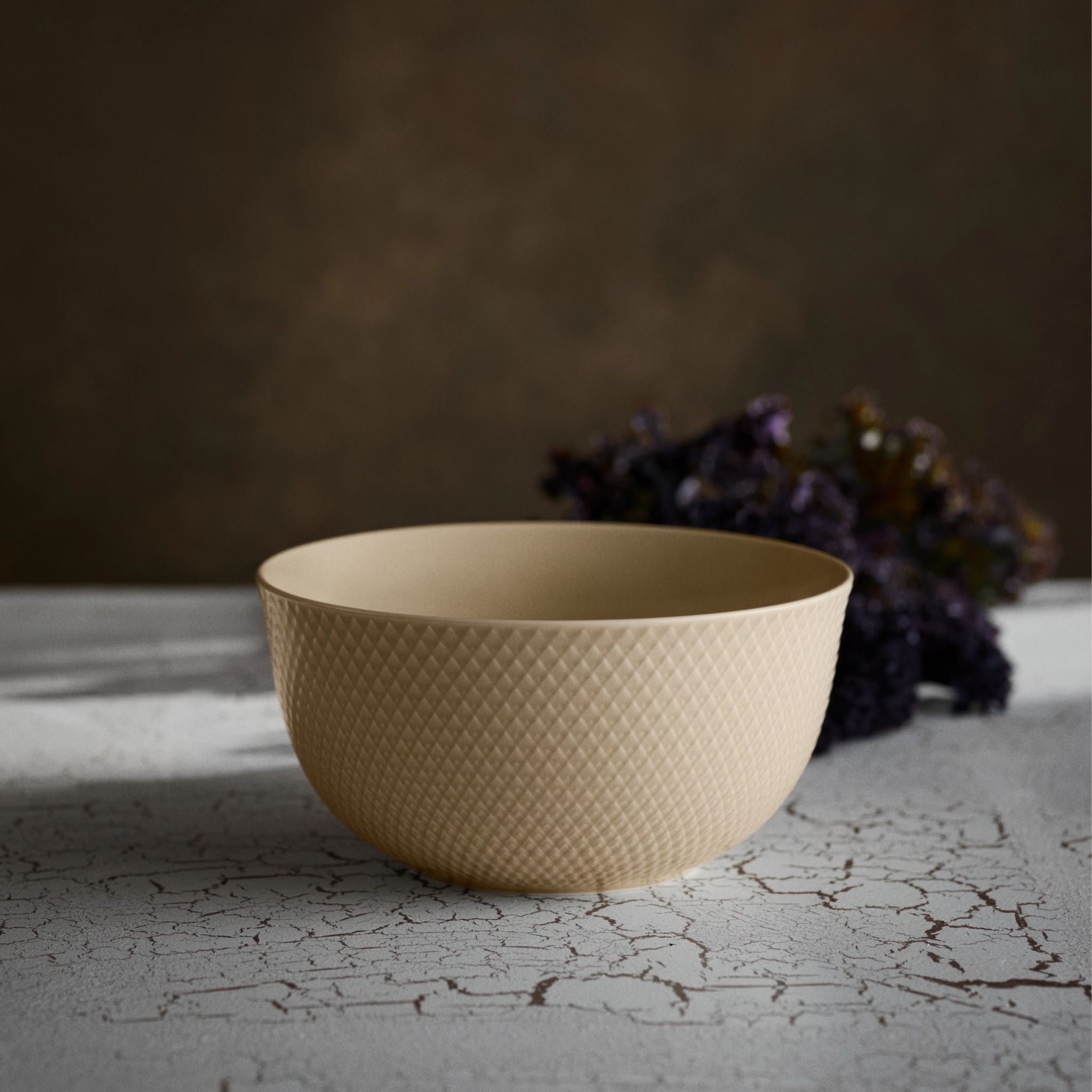 Beige textured bowl on a textured surface with a blurred background