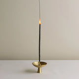 Incense stick burning in a gold holder on a neutral background