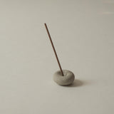 Incense stick in a mini light grey ceramic pebble incense holder 