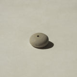 The underside of a mini light grey ceramic pebble incense holder 