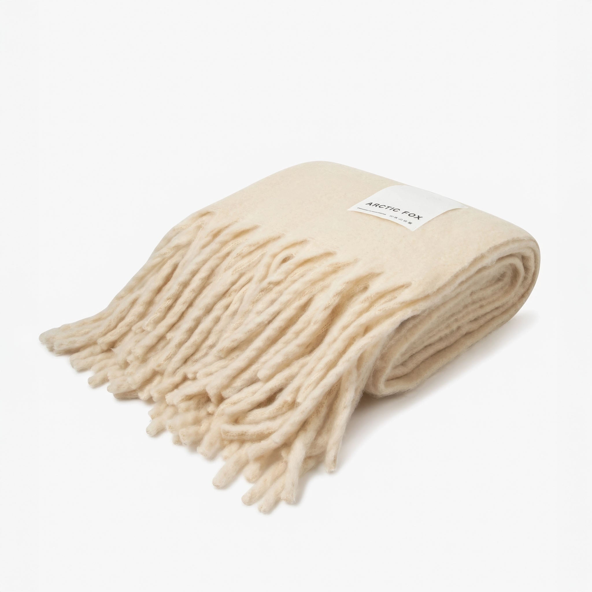 Folded beige throw with white fringe and white brand label Arctic Fox on a white background