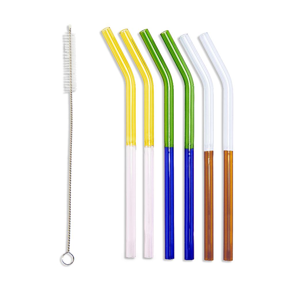 Set of six two-tone borosilicate glass straws in assorted colors (yellow-pink, green-blue, clear-orange) with a stainless steel cleaning brush on a white background.
