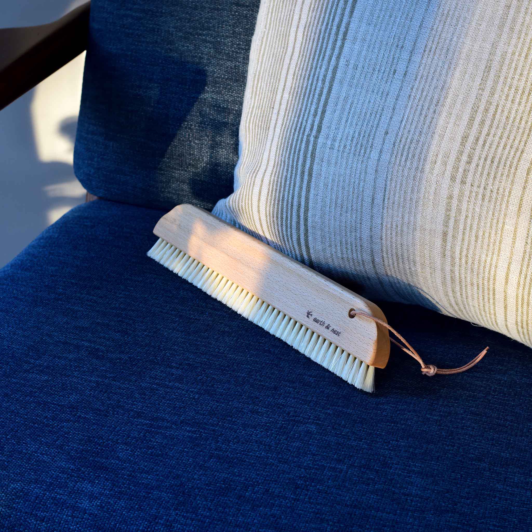 Angled full view of the Upholstery & Bed Brush on a blue sofa