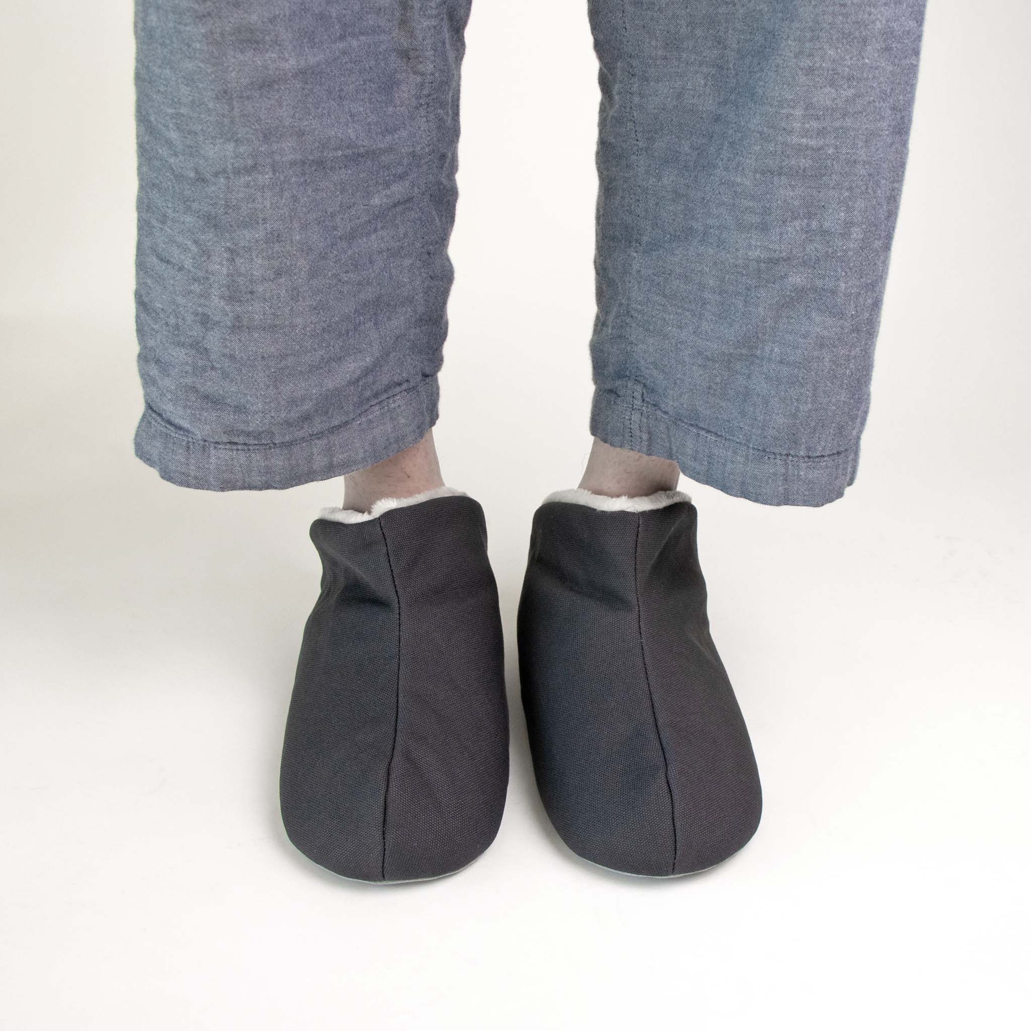 Person wearing a dark grey slipper on a light gray background