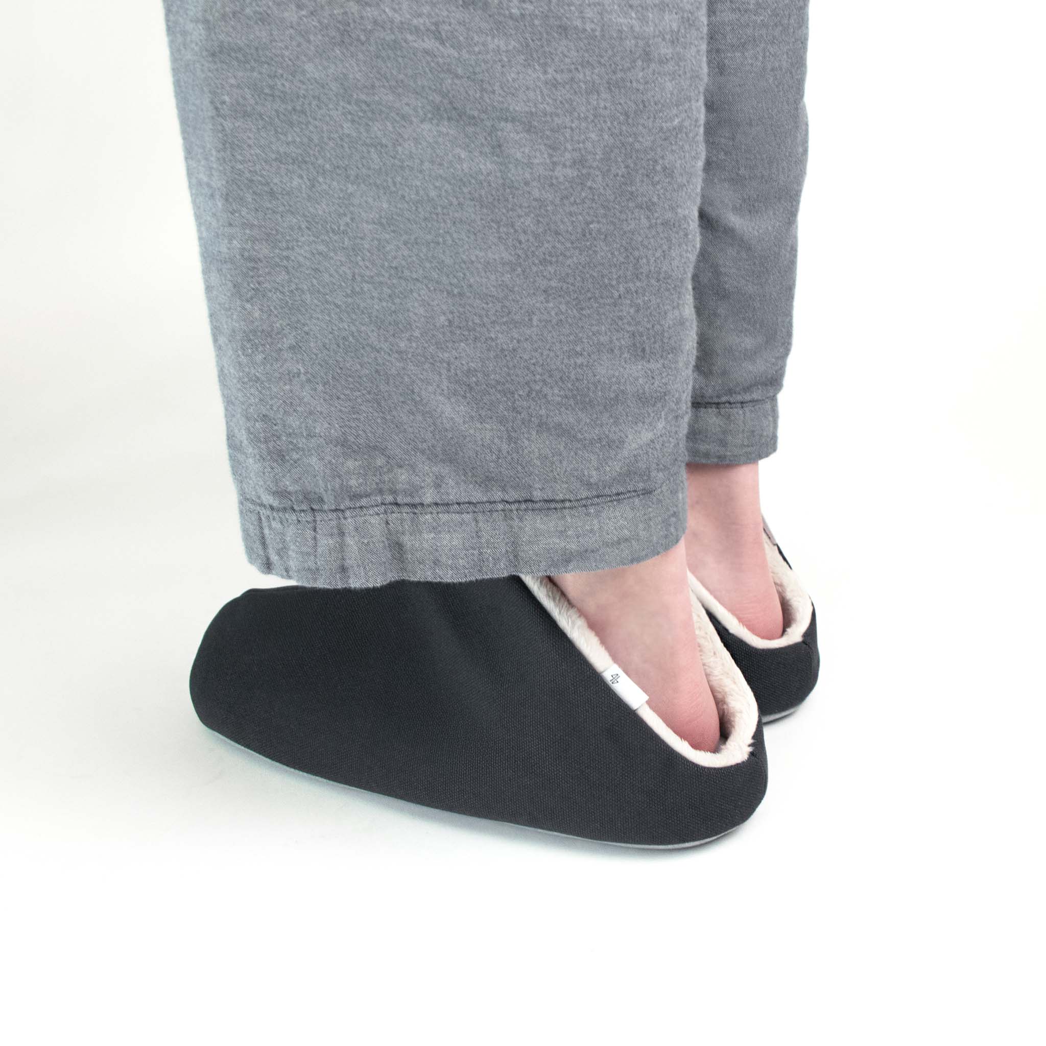 Person wearing a dark grey slipper on a light gray background