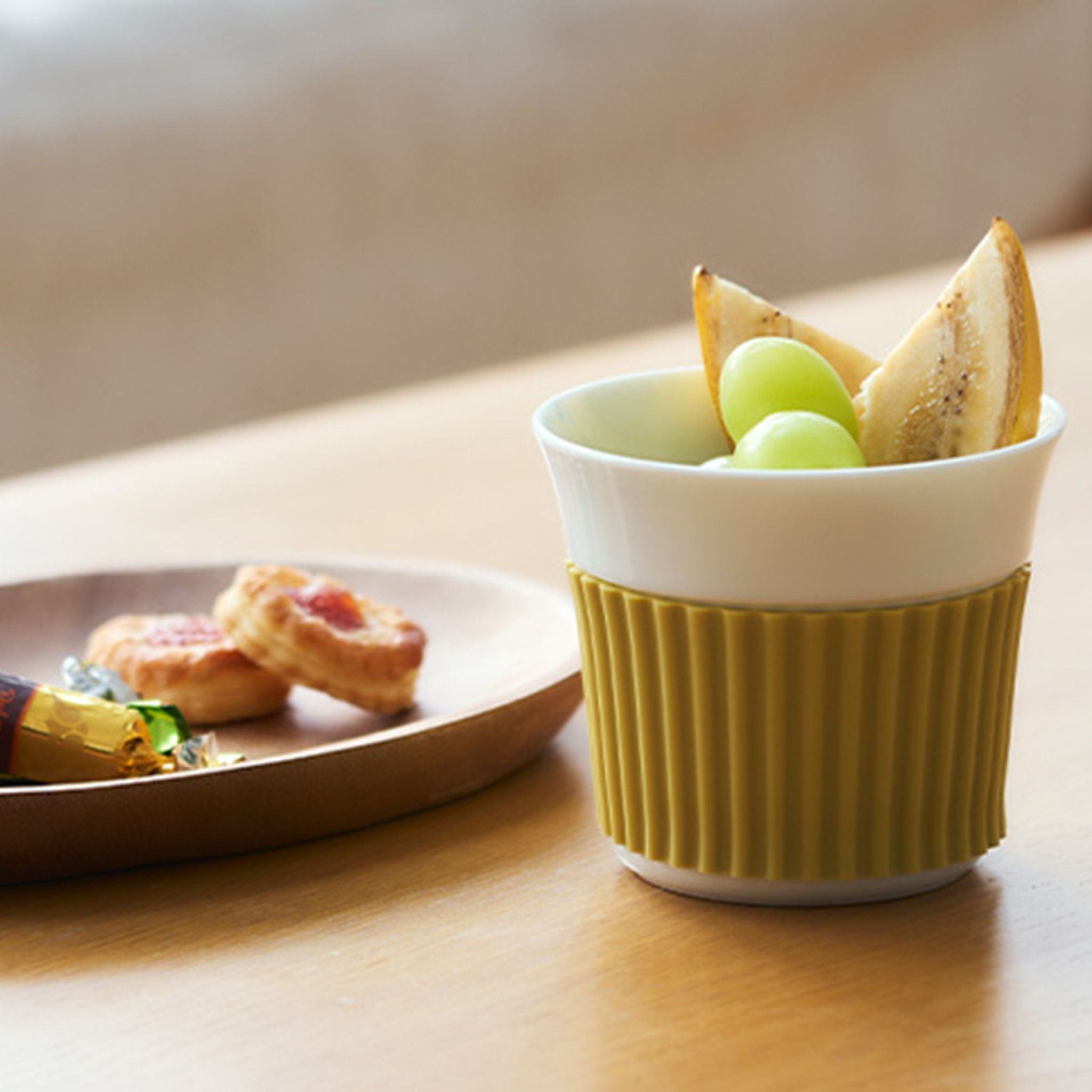 Green and white ceramic cup with snacks on a wooden table