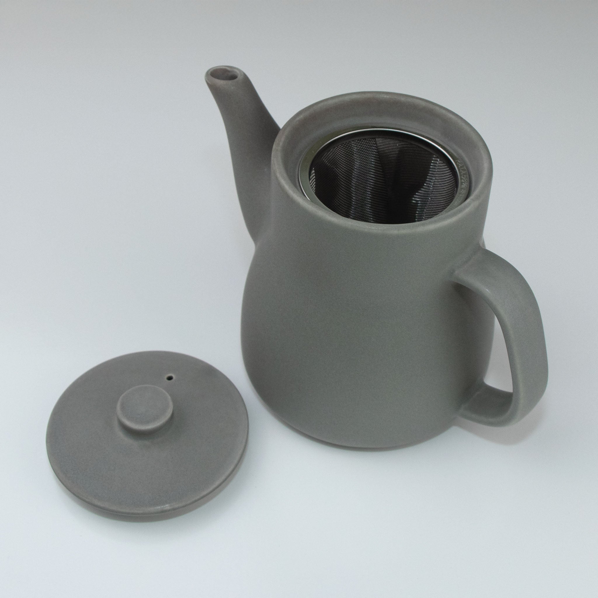 Gray teapot with a mesh filter on a white background