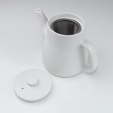 White ceramic teapot with a lid on a light gray background