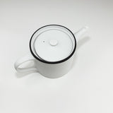 White teapot with black rim on a white background