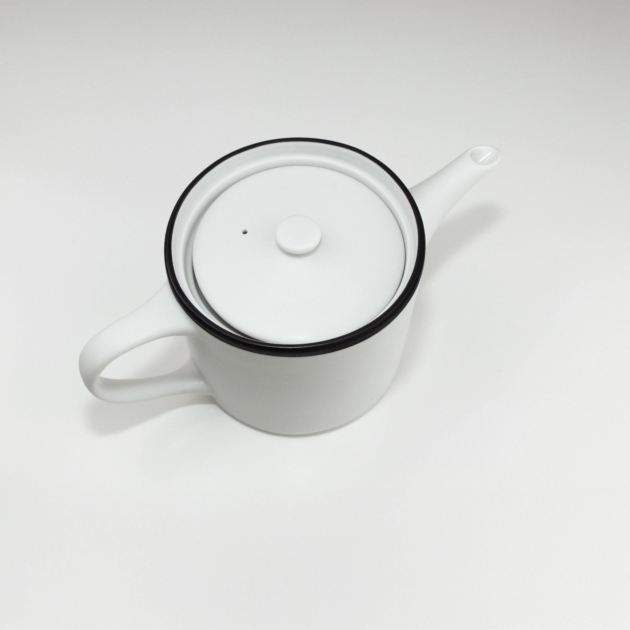 White teapot with black rim on a white background