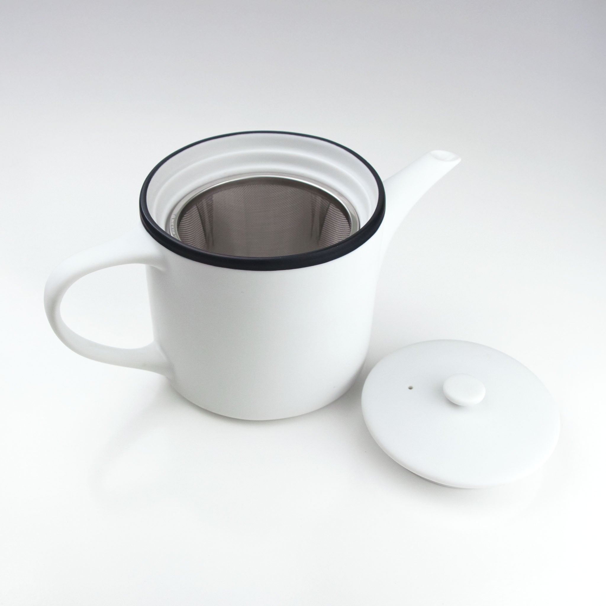 White teapot with a black rim on a white background
