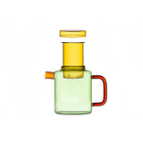 Colorful glass teapot with amber lid, yellow infuser, light green body, and red handle, shown against a white background.