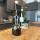 Glass bottle with dark liquid on a wooden surface in a kitchen setting