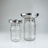 Two glass jars with stainless steel funnels on a white background